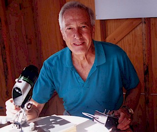 Photo of George T Keene at the light table of this camera obscura where the image is displayed. He is using a custom magnifier that allows him to get a closer view and even attach a camera for photography,